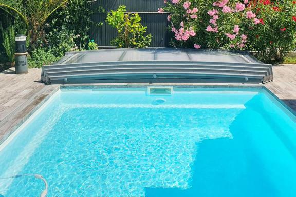 abri de piscine néosmart replié et ouvert sur la piscine