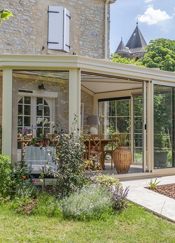 véranda ton pierre jardin d'hiver Akena avec vue sur le jardin arboré