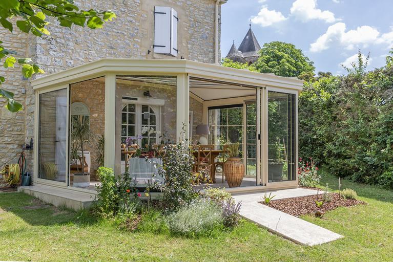 véranda ton pierre jardin d'hiver Akena avec vue sur le jardin arboré